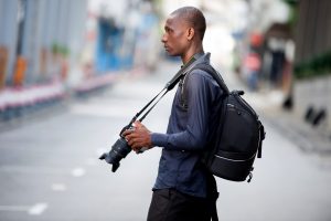 Un jeune étudiant explore une nouvelle ville et une nouvelle culture tout en se promenant dans les attractions touristiques avec un appareil photo analogique et un sac à dos.
