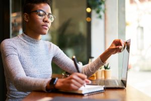 Une femme noire sérieuse écrit des plans dans un bloc-notes