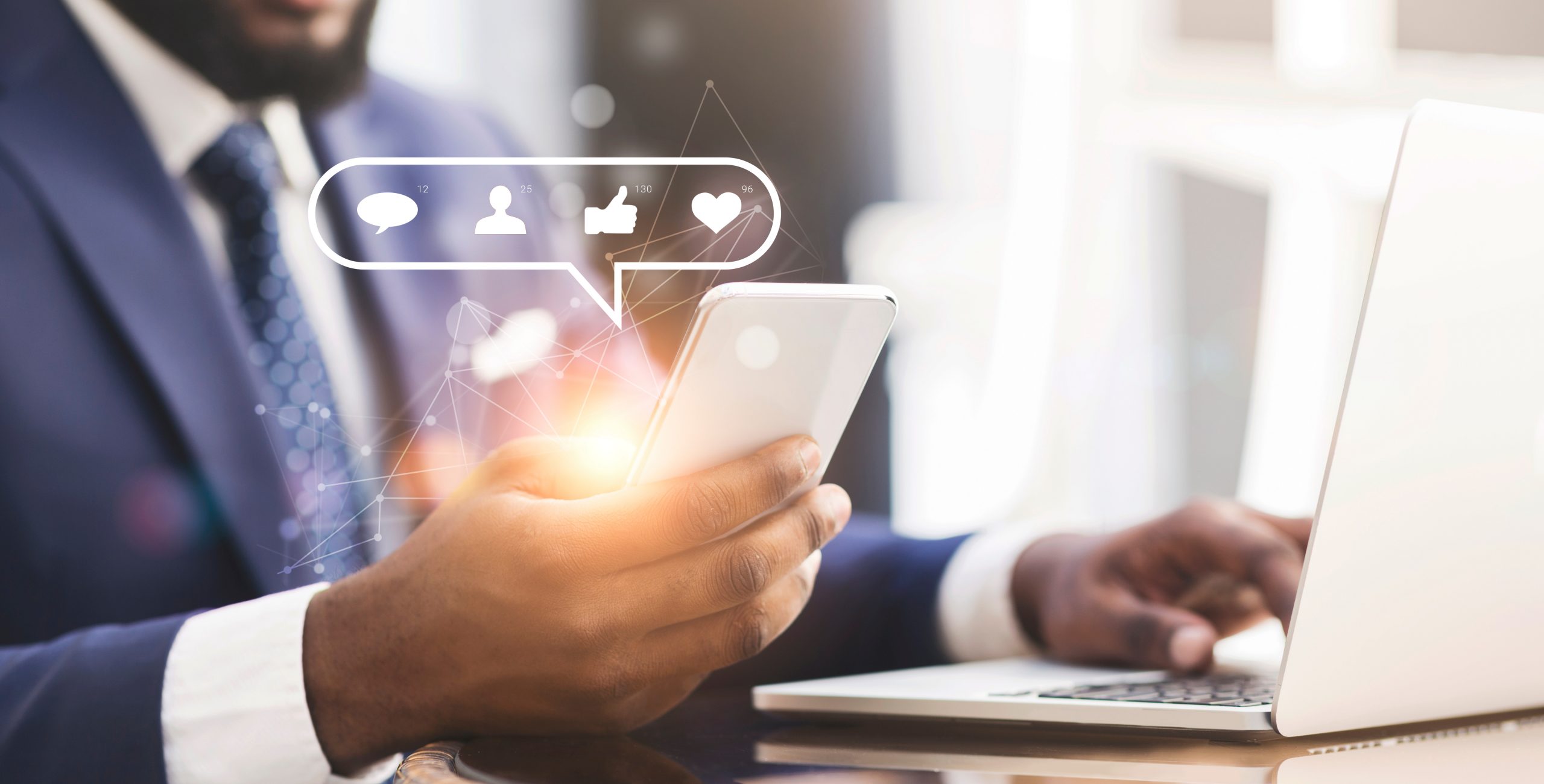 Web marketing specialist with mobile phone and laptop creating engaging social media content
