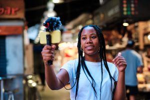 Jeune influenceuse latino-américaine utilisant son smartphone et son micro pour diffuser en direct. Photo haute qualité.