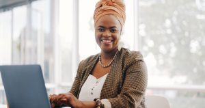 Portrait, visage ou femme noire dans un immeuble de bureaux, souriante et travaillant sur du marketing par e-mail en ligne. Ressources humaines, startup ou travailleur africain motivé, ambitieux ou en phase avec la réussite.