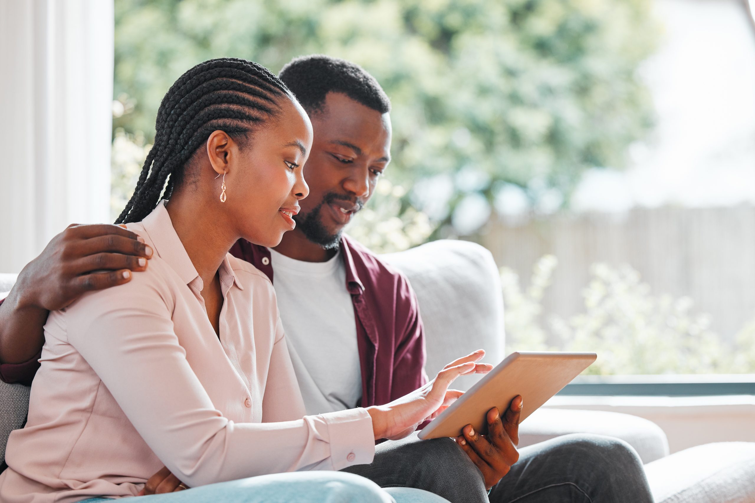 People, black couple and smile with tablet on sofa at home with browsing internet for house insurance options. Family, relationship and happy or satisfied on website for life policy and funeral cover.