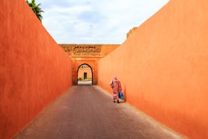 Une femme musulmane se promène dans une rue étroite et colorée avec un portail à Marrakech