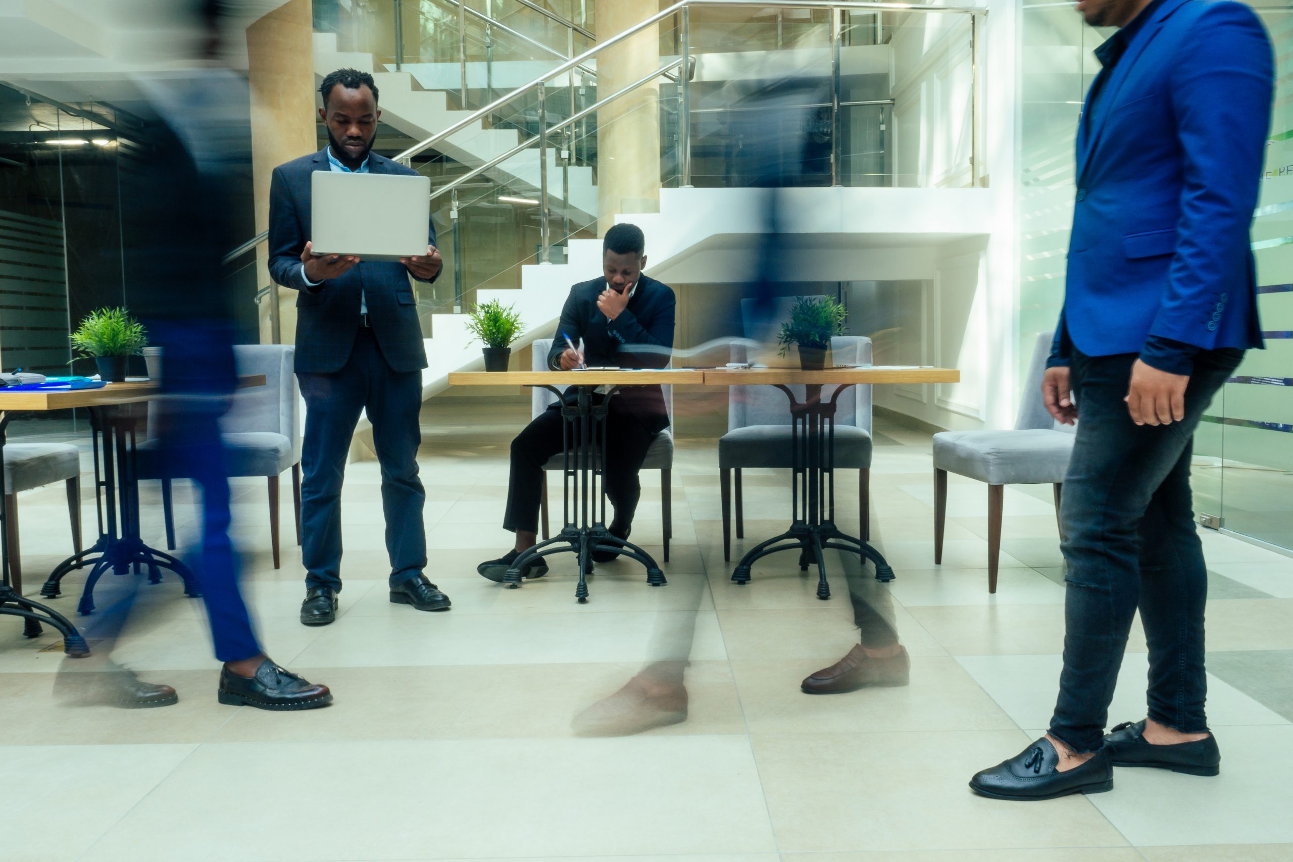 africa american business man working with laptop,blurred people walking next to him in big office