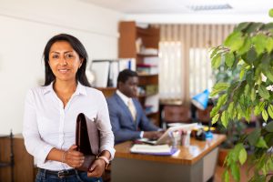 Femme d'affaires hispanique prospère debout dans un bureau avec une mallette