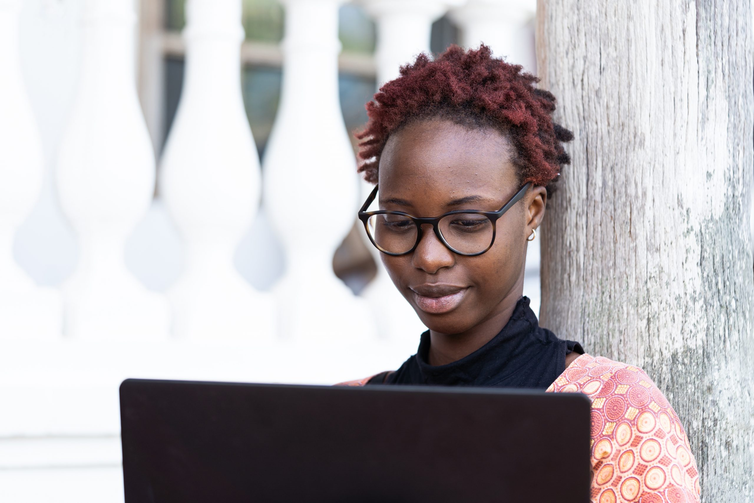Smart African blogger with stylish glasses and afro-hairstyle checking out her mail and sharing content on social media