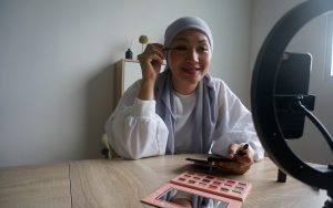 Une blogueuse beauté asiatique enregistre une vidéo tutorielle maquillage pour la partager sur les réseaux sociaux. Photographie en basse lumière.