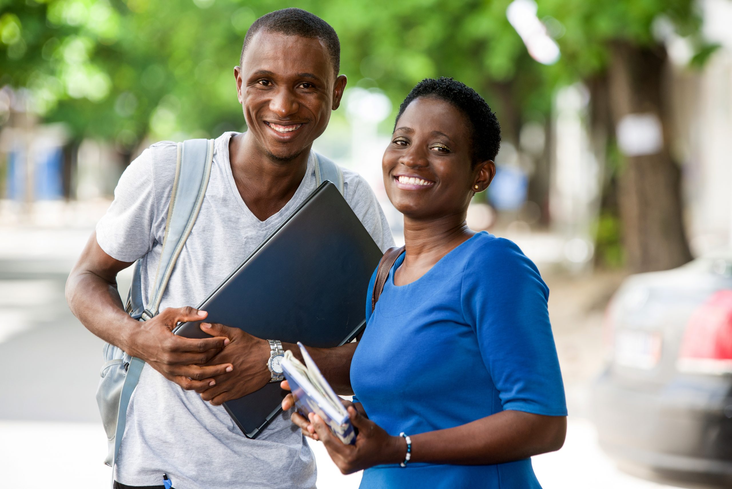 two young happy students showing thumbs outdoors in the city in summer